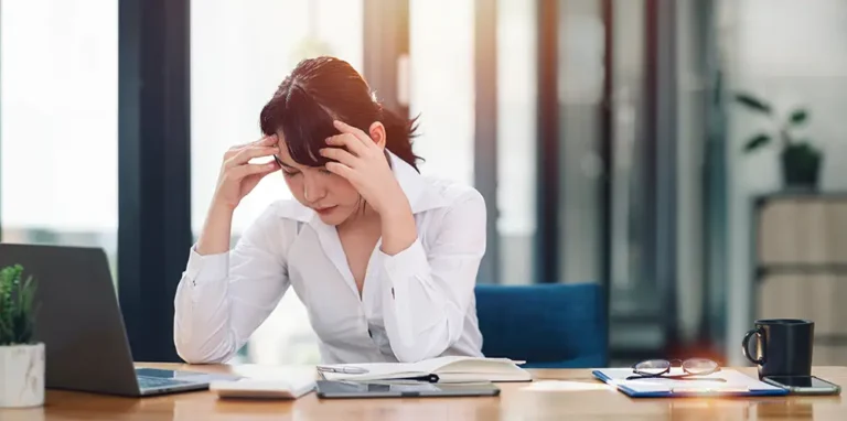 woman at work holding face and grimacing